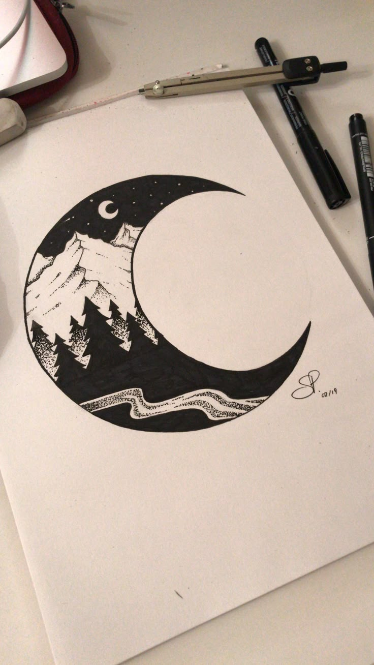 a drawing of a crescent moon with mountains and trees in the background, on top of a white paper