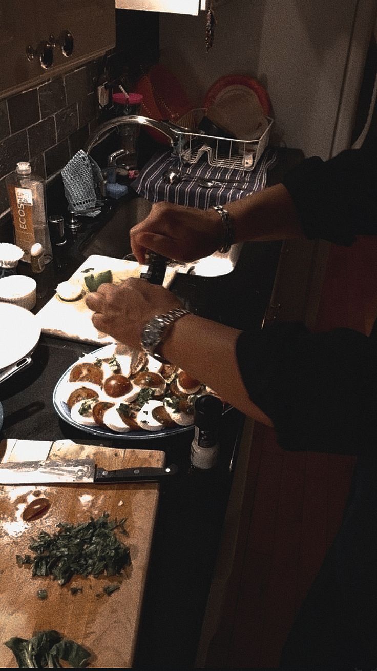 two people are preparing food in the kitchen