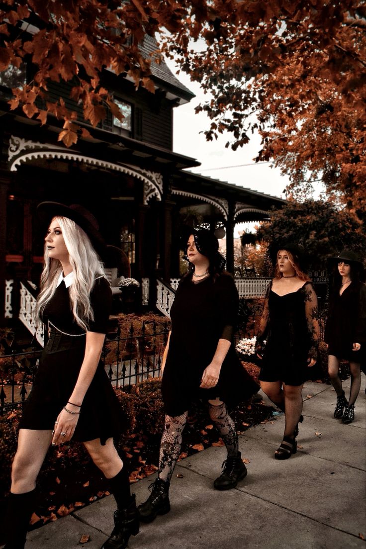 three women walking down the sidewalk in front of a house, one wearing black and white