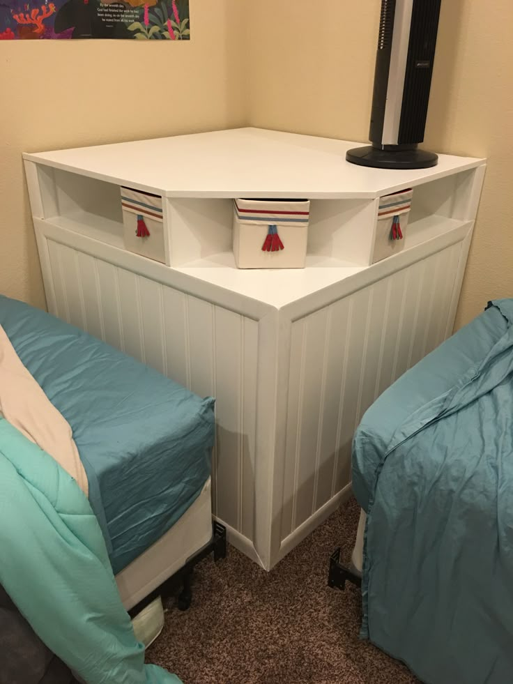 two beds in a small room with blue sheets and pillows on the bottom bed, next to an entertainment center