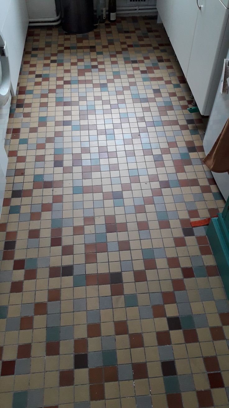 a tiled floor in a kitchen with white cabinets