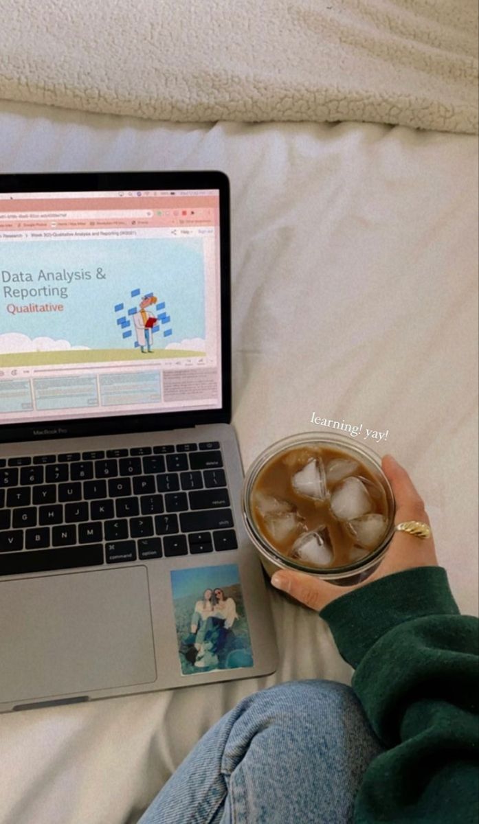 a person sitting on a bed with a laptop and drink in front of their lap