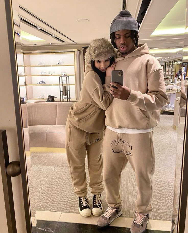 a man and woman standing in front of a mirror looking at a cell phone together