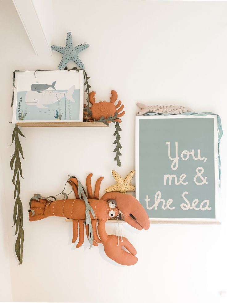 two wooden sea animals are hanging on the wall next to pictures and other items that say you, me & the sea