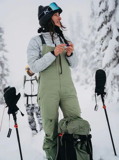 a woman standing in the snow with ski equipment