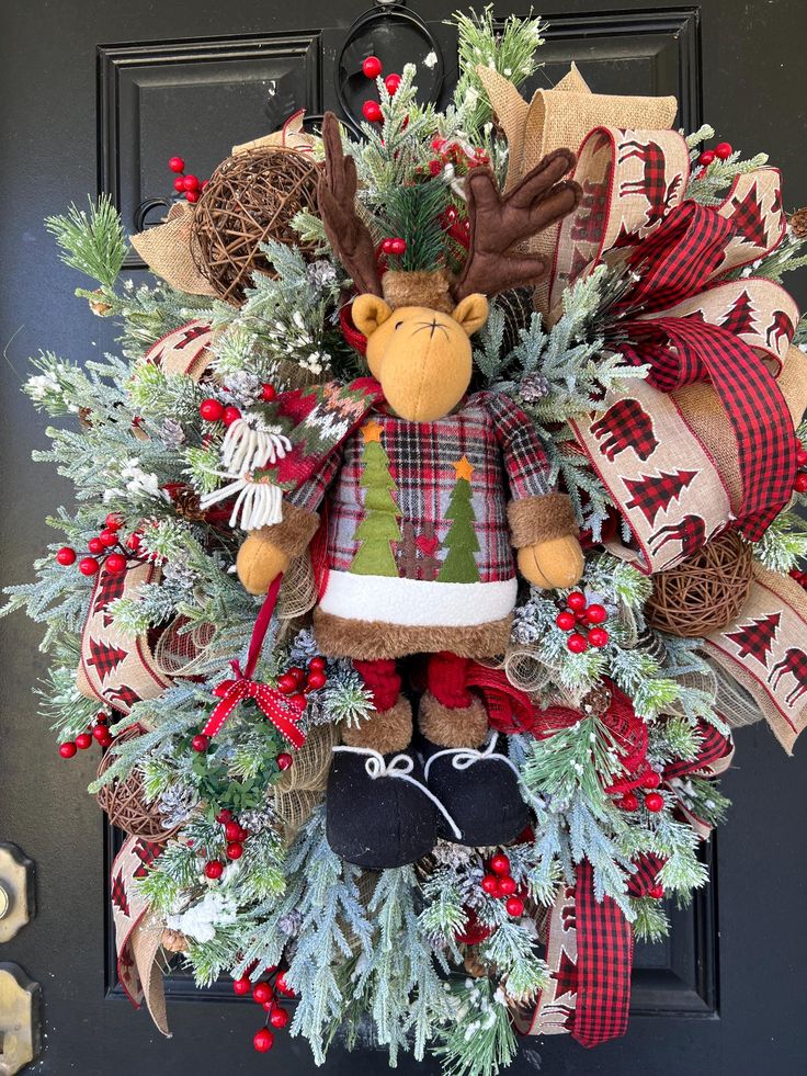 a christmas wreath with a stuffed animal hanging from it's side on a door