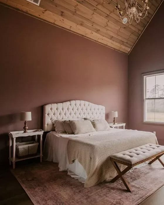 a bedroom with a white bed and a chandelier hanging from the ceiling above it