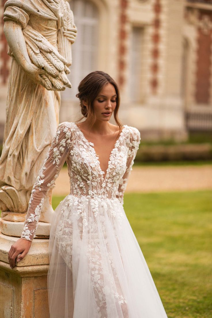 a woman standing next to a statue wearing a wedding dress