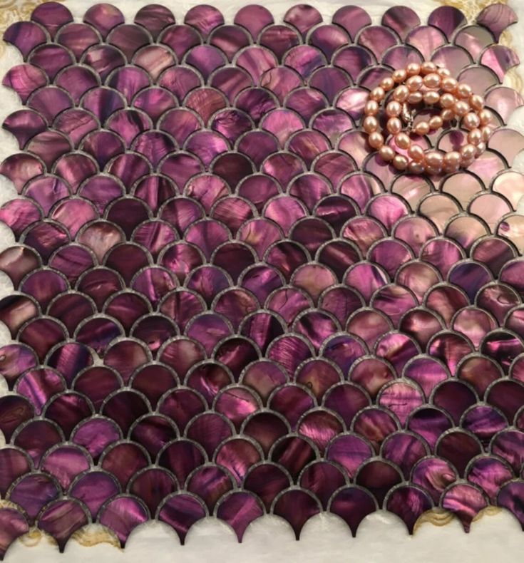 a purple and white mosaic tile with a beaded ring on the bottom half of it