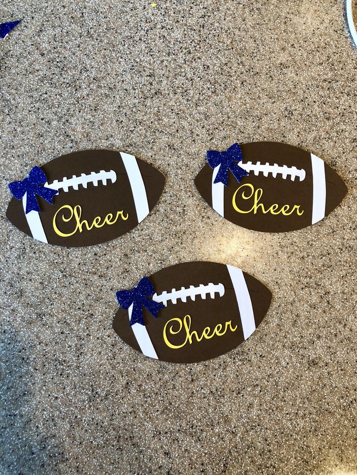 three football shaped magnets with the word cheer on them sitting on a counter top