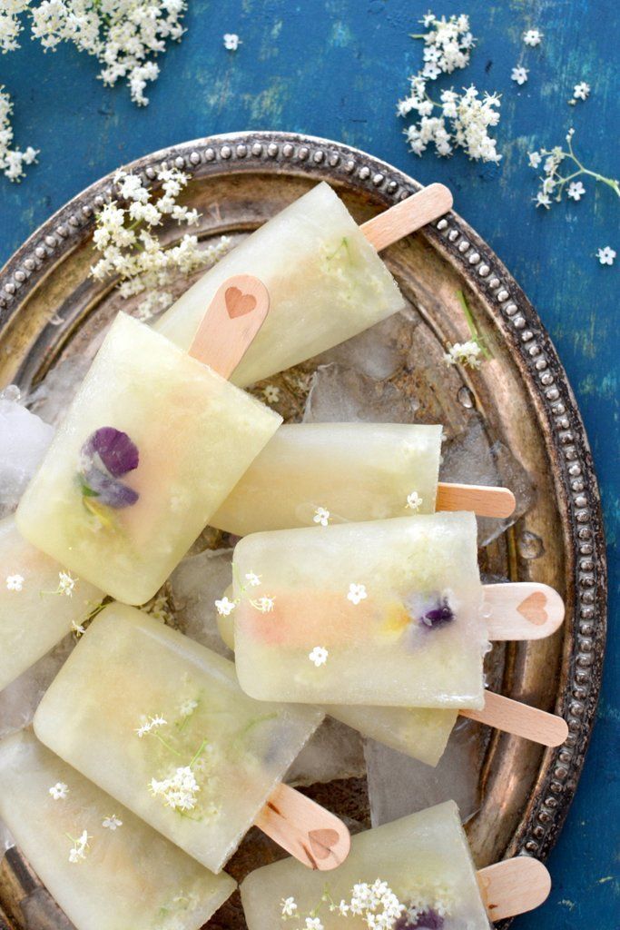 popsicles with flowers on them are sitting on a silver plate next to white flowers