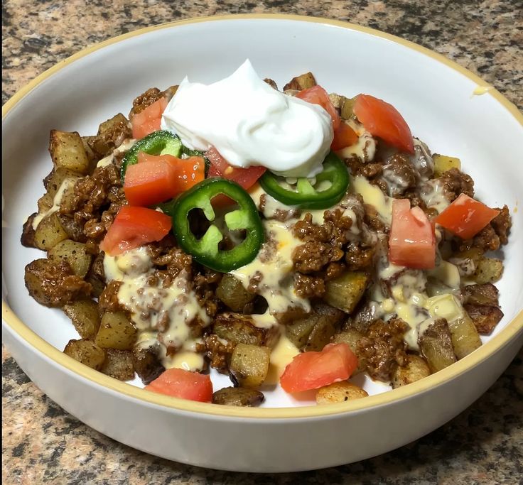 a white bowl filled with food and topped with sour cream on top of a table