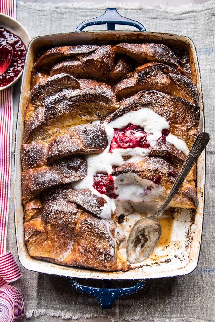 a blue dish filled with french toast covered in powdered sugar and berries next to a bowl of jelly