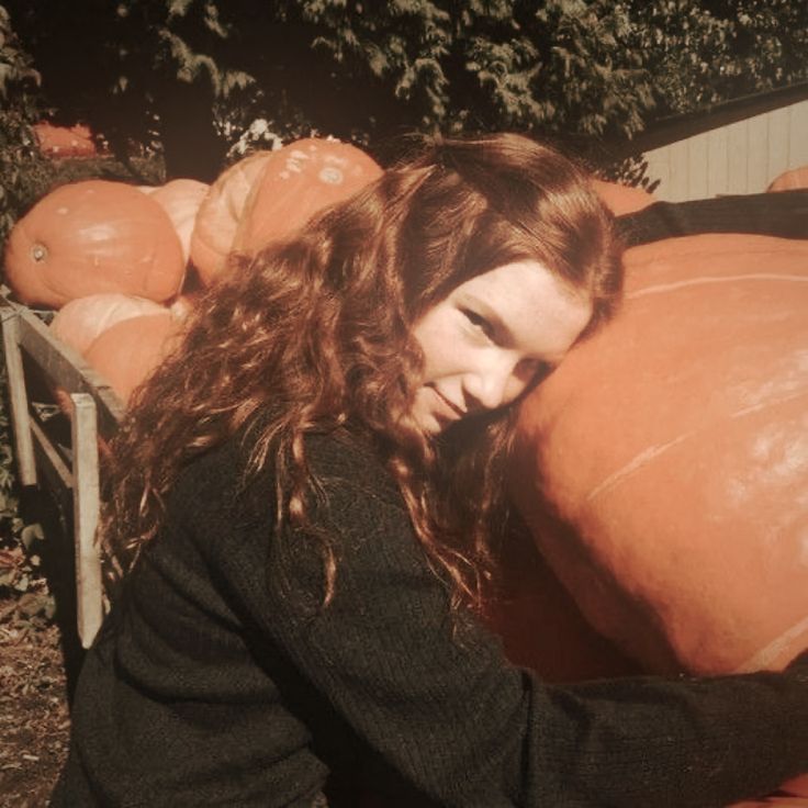 a woman is holding large pumpkins in her hands