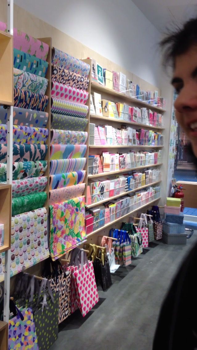 a man standing in front of a store filled with lots of colorful bags and gifts