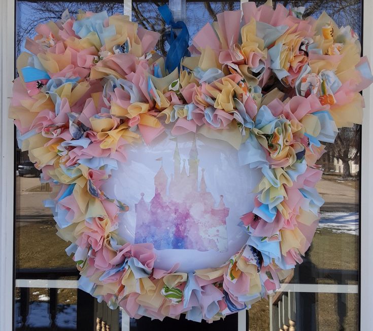 a pink and yellow wreath with a castle on it in front of a window sill