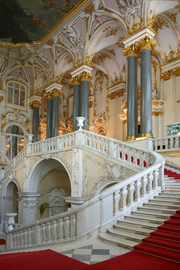 an ornate staircase in the middle of a room with red carpet and gold trimmings