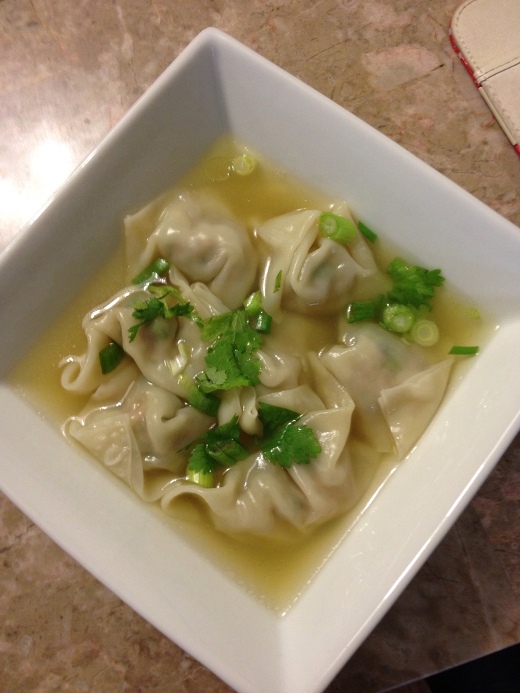 a white bowl filled with dumplings and broccoli on top of a table