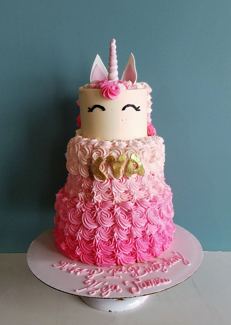 a cake decorated with pink and white icing has a unicorn face on the top