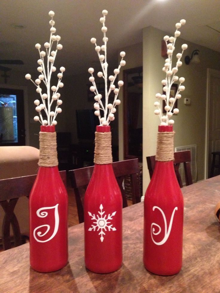 three red wine bottles with white snowflakes in them sitting on a counter top