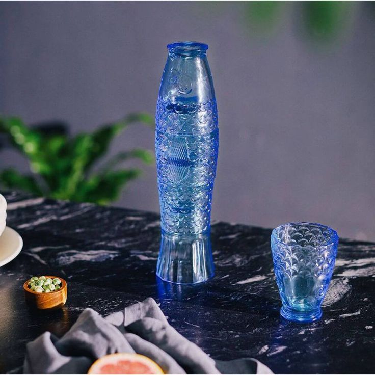 a blue vase sitting on top of a table next to two cups and saucers