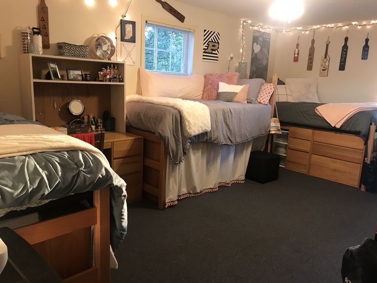 a dorm room with two beds and desks