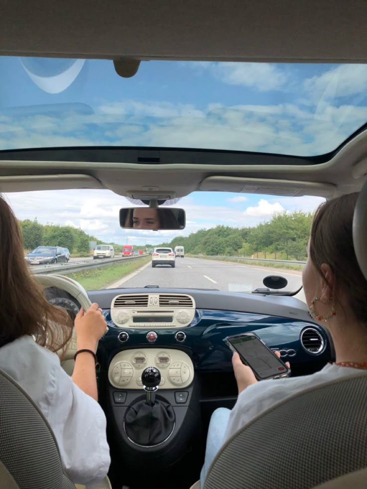 two women are sitting in the driver's seat of a car