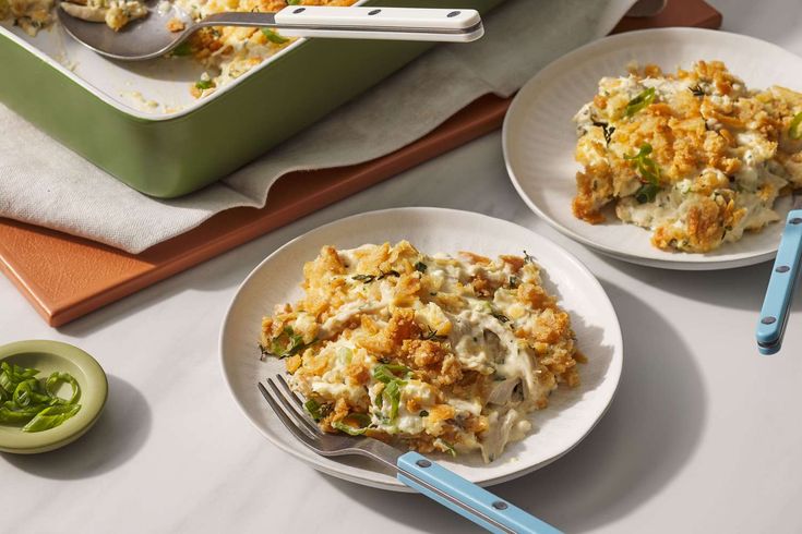 two white plates topped with food next to a green casserole dish