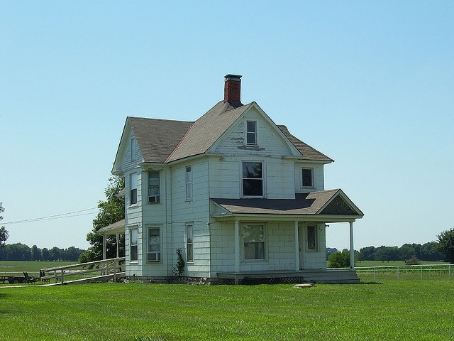 an old white house sitting on top of a lush green field