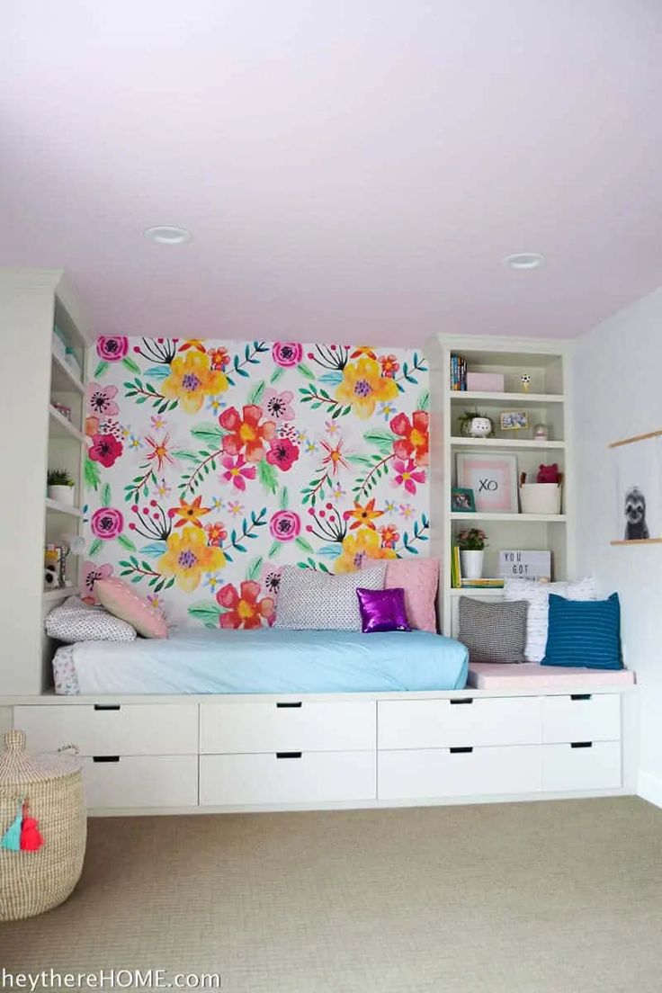 a bedroom with white shelves and colorful wallpaper