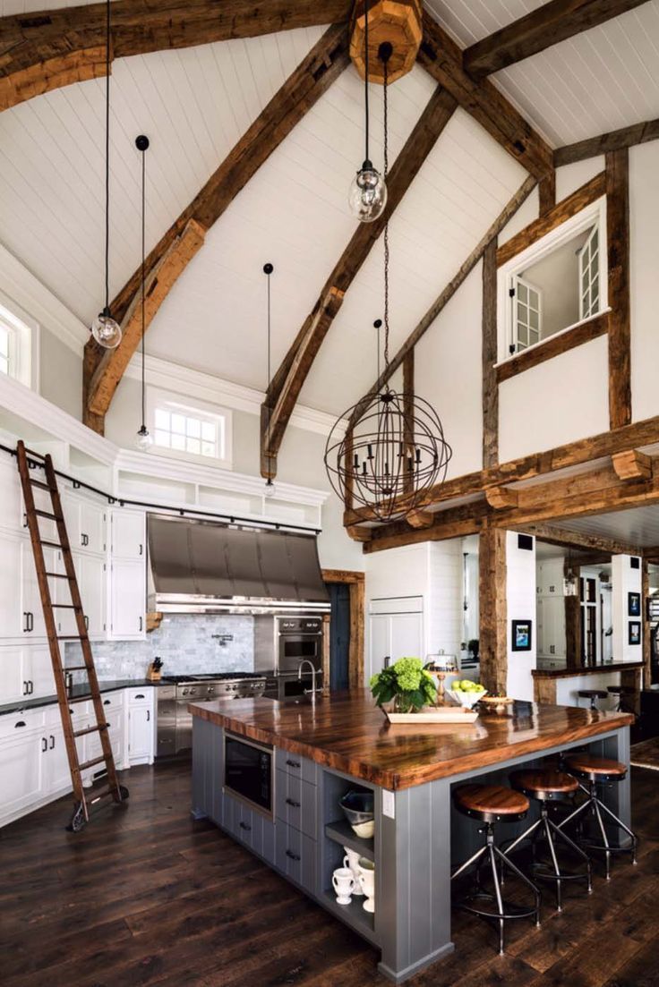 a large kitchen with an island and ladders in it's center area, surrounded by wooden beams