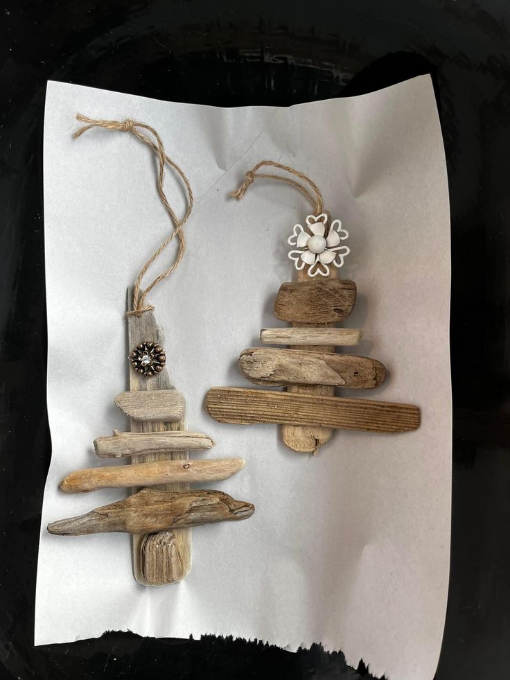 two pieces of driftwood are sitting on top of each other, one is holding a snowflake ornament