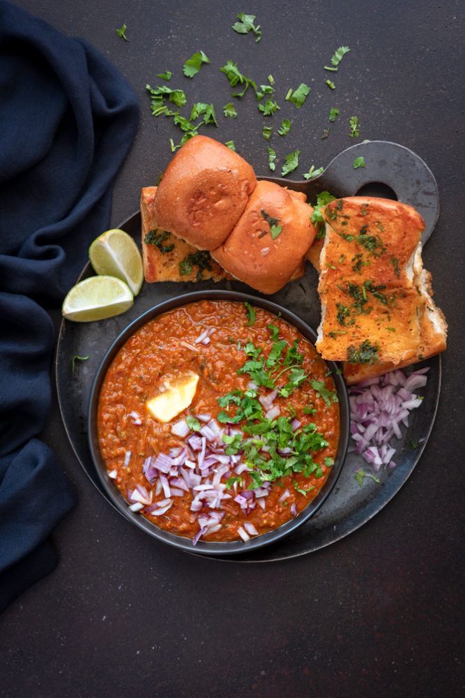 a black plate topped with beans and bread next to a slice of lime wedges