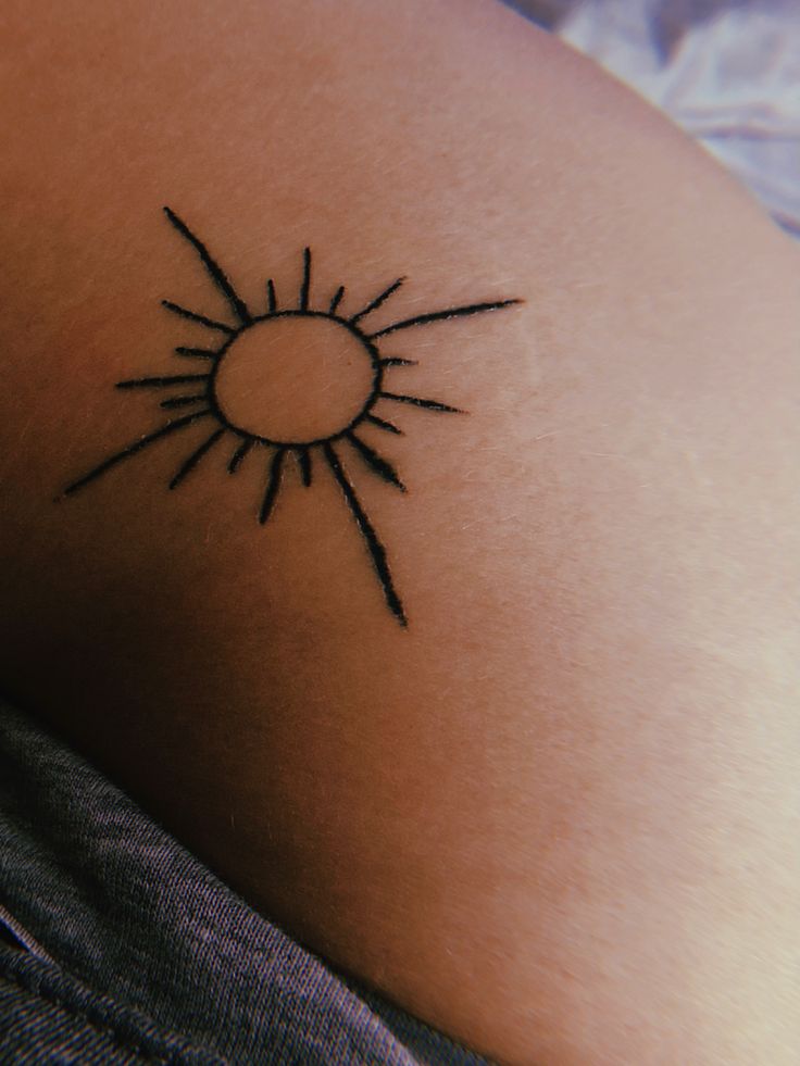 a small sun tattoo on the back of a woman's shoulder