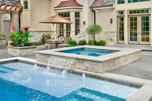 an outdoor swimming pool with a waterfall and patio furniture in the back ground, surrounded by landscaping