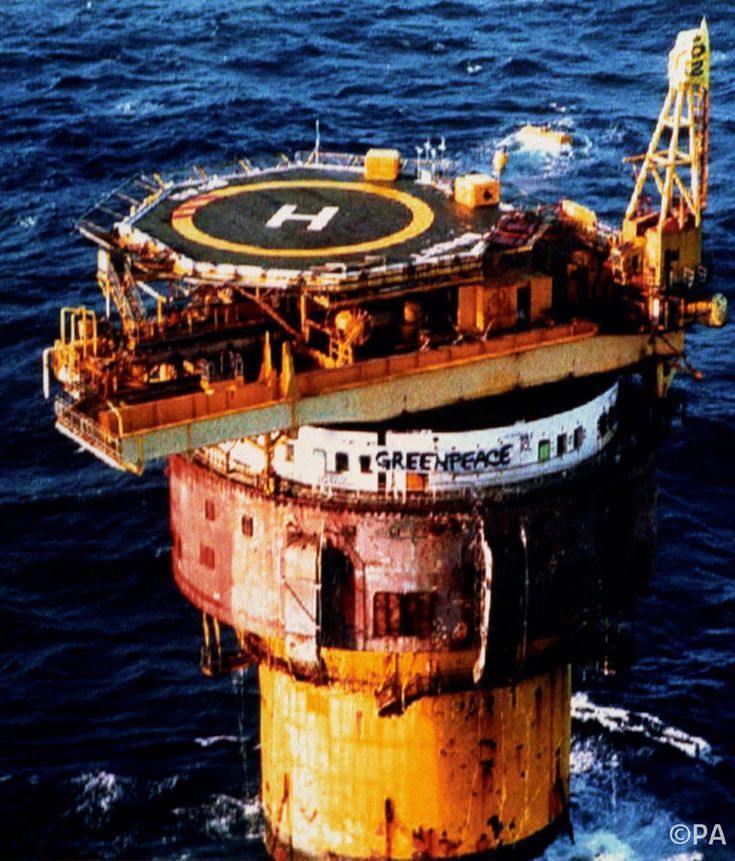 an oil platform in the middle of the ocean with water around it and two yellow platforms on top