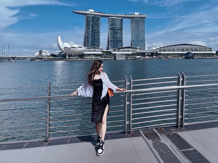 a woman standing on the edge of a pier next to water