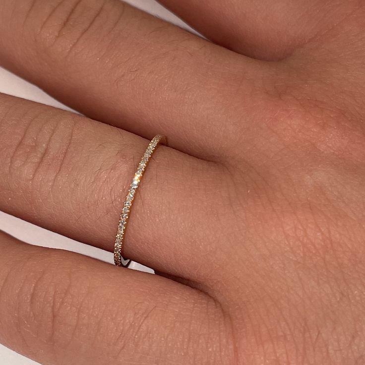 a woman's hand with a diamond ring on her left hand and the middle finger