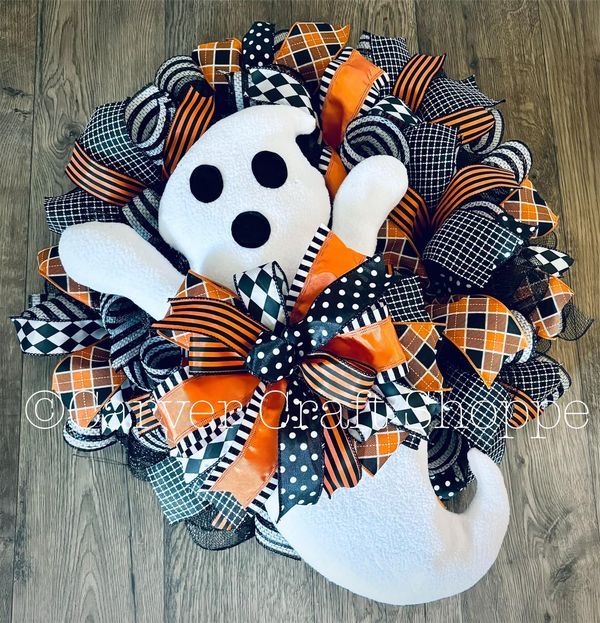 a halloween wreath with a white dog wearing a black and orange checkered bow on it