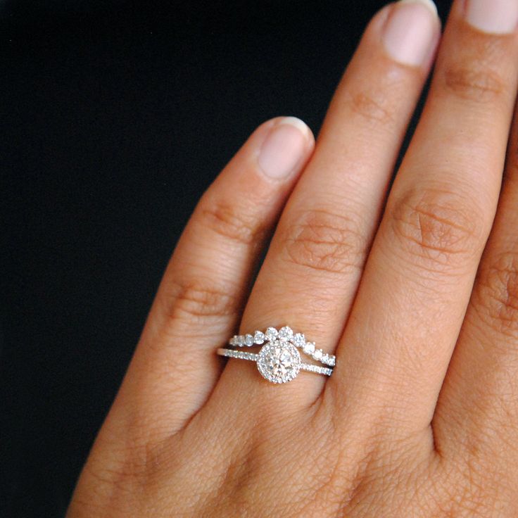 a woman's hand with a diamond ring on top of her finger and an engagement band