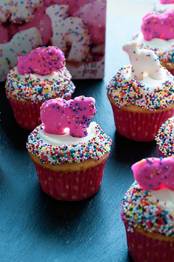 cupcakes with pink frosting and sprinkles are on a table