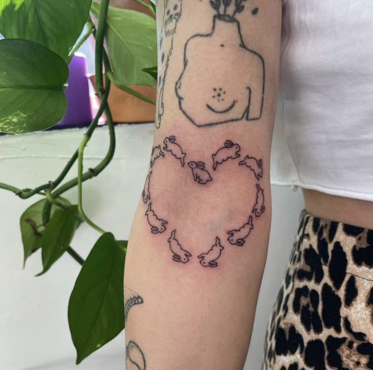 a woman's arm with tattoos on it and a drawing of a dog in the shape of a heart