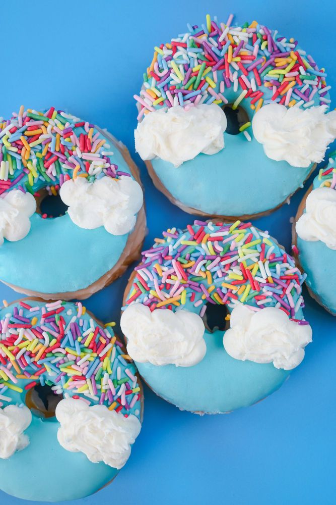 six donuts with frosting and sprinkles on blue background, top view