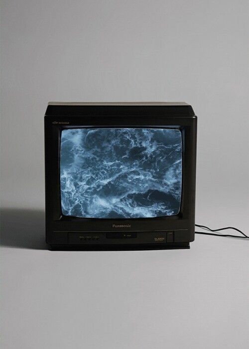 an old television sitting on top of a white table next to a corded phone