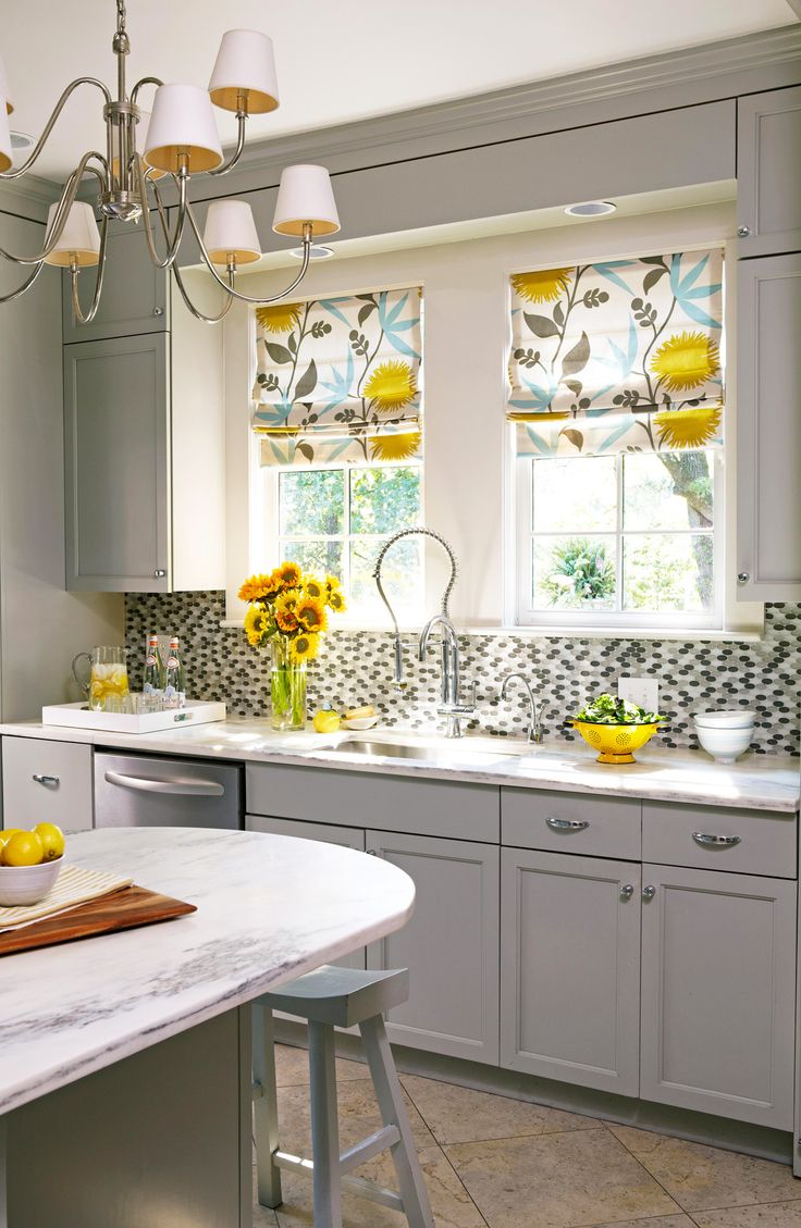 a kitchen with white cabinets and yellow sunflowers in the window sill above the sink