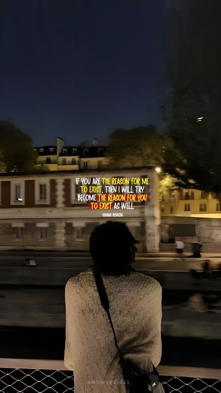 a woman is looking out at the city from behind a fence with a quote written on it