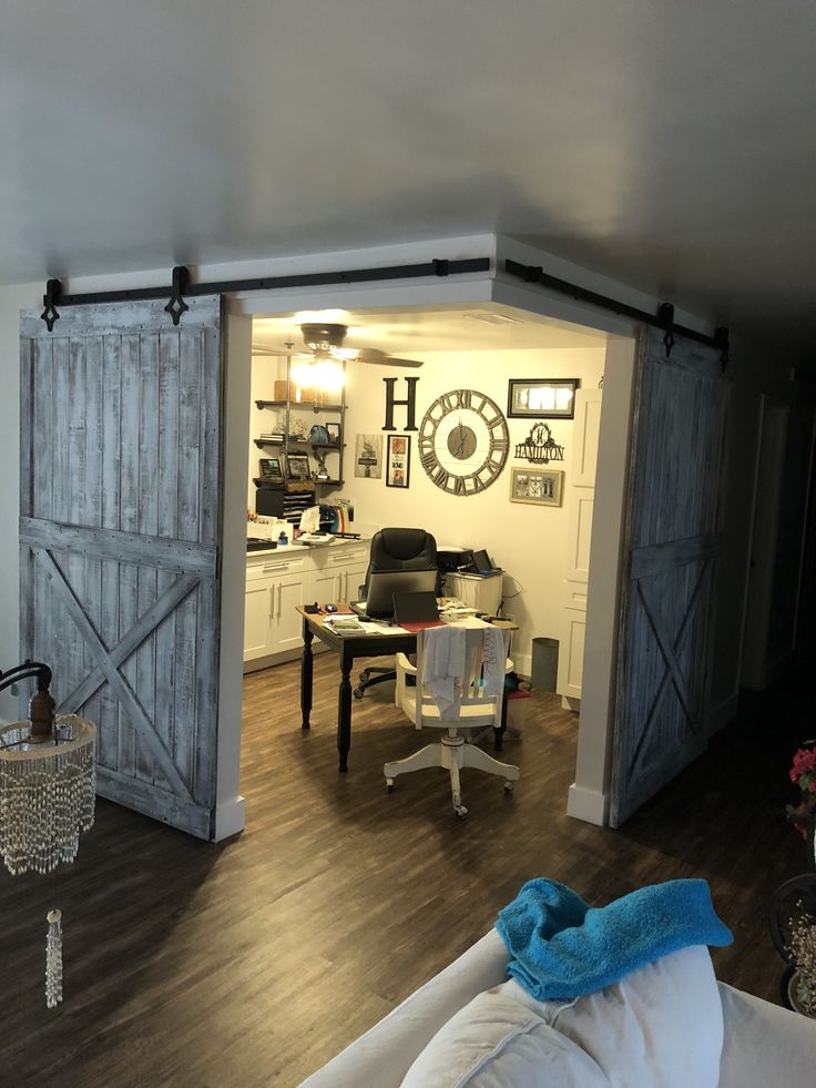 a living room filled with furniture and a sliding door leading to an office area that has a desk