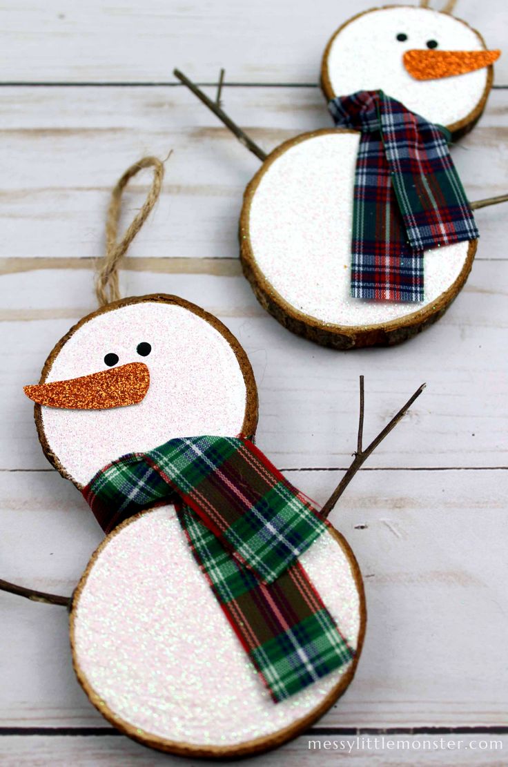 three snowmen made out of wood slices with plaid scarves and scarfs on them