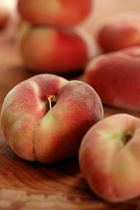 three peaches sitting on top of a wooden table