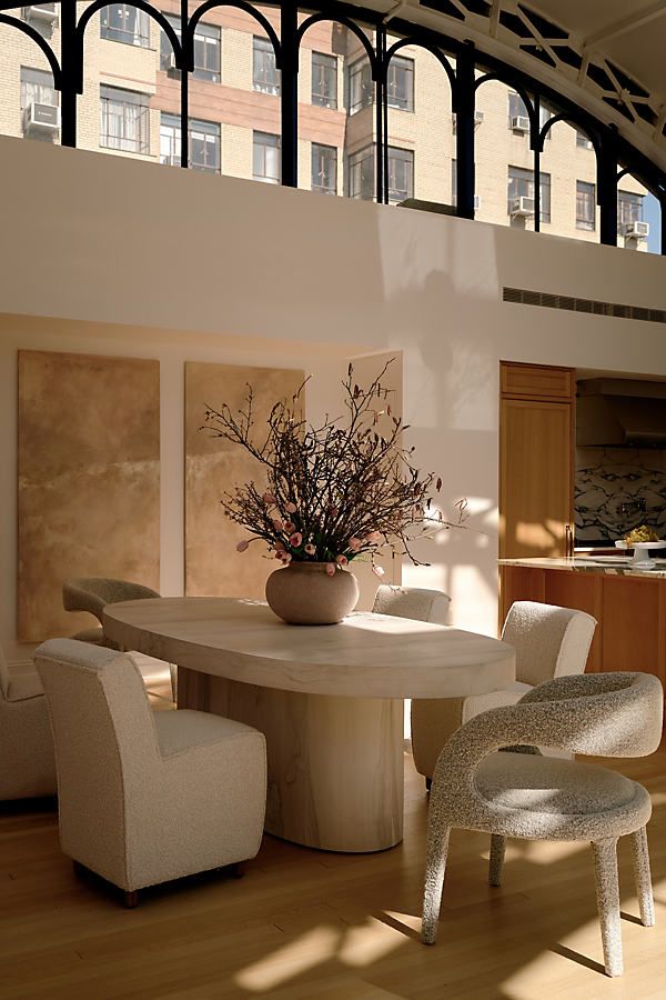 a dining room table with chairs and a vase filled with flowers on top of it